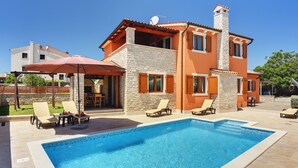 Ein zweistöckiges Haus mit Swimmingpool, Außenbereich zum Sitzen und einer Stein-Fassade.