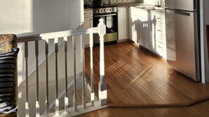A kitchen with white cabinets, a stainless steel refrigerator, a stove, and a wooden floor. - The Blue Dove (Shenandoah Farms)