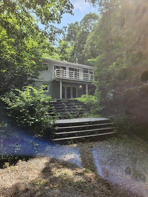 A two-story house with a balcony, surrounded by dense greenery. - The Blue Dove (Shenandoah Farms)