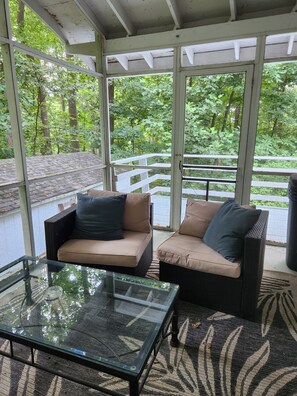 A covered outdoor seating area with wicker furniture and a glass table. - The Blue Dove (Shenandoah Farms)