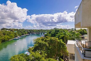 A river with boats, a bridge, and lush greenery. - Elegant and Stylish, Centric La Romana 3BR Apt, Stunning River Views (La Romana)