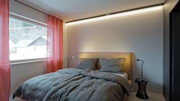 Un dormitorio moderno con una cama, una mesita de noche y un ventanal con cortinas.