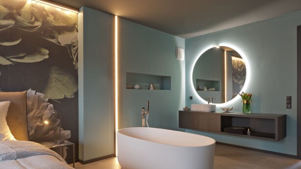 A modern bathroom with a freestanding bathtub, a round mirror with a light, and a minimalist vanity. - Z Apartment by Interhome (Schladming)