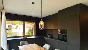A modern kitchen with dark cabinetry, a wooden dining table, and pendant lighting. - Z Apartment by Interhome (Schladming)