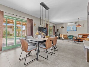 A modern living room with a dining area, large windows, and a view of the outside. - Villa Lunistra by Interhome (Cere)