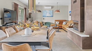 Een moderne woonkamer met een eethoek, een televisie en een open haard.