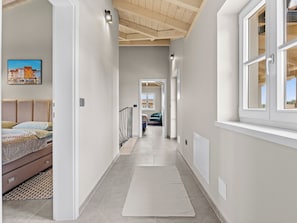 Un couloir avec un lit, une fenêtre et une vue sur un immeuble.