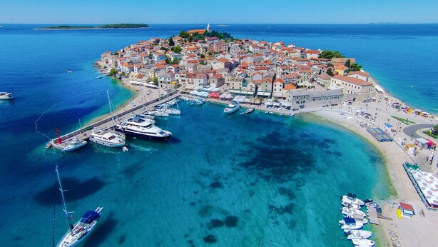 An aerial view of a coastal town with a marina, clear blue waters, and a prominent church on a hill. - Villa Laguna 3 Ferienwohnung für 4 Personen by Interhome (Primošten)