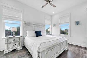 A bedroom with a white bed, two bedside tables, a ceiling fan, and large windows. - The Magnolia by Stay on 30a (Inlet Beach)