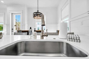 A modern kitchen with a stainless steel sink, a hanging pendant light, and a white countertop. - The Magnolia by Stay on 30a (Inlet Beach)