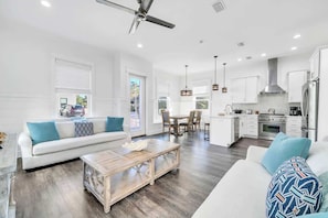 A modern living room with a sofa, coffee table, and dining area with chairs. - The Azalea by Stay on 30a (Inlet Beach)