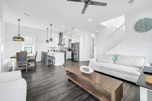 A modern living room with a white sofa, wooden coffee table, and a dining area with a white table and chairs. - The Jasmine by Stay on 30a (Inlet Beach)