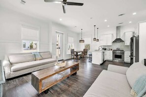 Una sala moderna con sofá, mesa de centro, comedor y cocina.