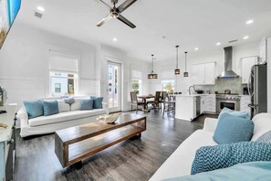 A spacious living room with a sofa, coffee table, and dining area. - The Lily by Stay on 30a (Inlet Beach)