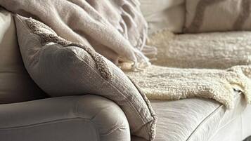 A beige sofa with a textured throw blanket and a matching pillow.