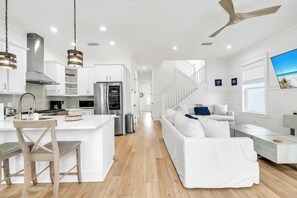 A modern kitchen with white cabinets, a central island, and a ceiling fan. - The Lotus by Stay on 30a (Inlet Beach)