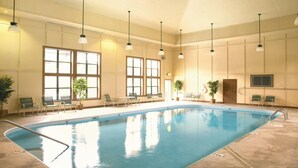 An indoor swimming pool with clear water, surrounded by chairs and potted plants, with large windows allowing natural light. - Spacious 2BR Smoky Mountains Condo - Sleeps 8 - Spring Break Weekend Getaway (Sevierville)