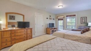A bedroom with two beds, a dresser, a television, and a door leading to a balcony.