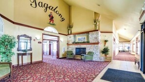 A spacious lobby with a red carpet, a stone fireplace, and a large mirror on the wall.