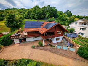 A two-story house with a sloped roof, solar panels, and a brick driveway. - Look wide by Interhome (Oberelsbach)