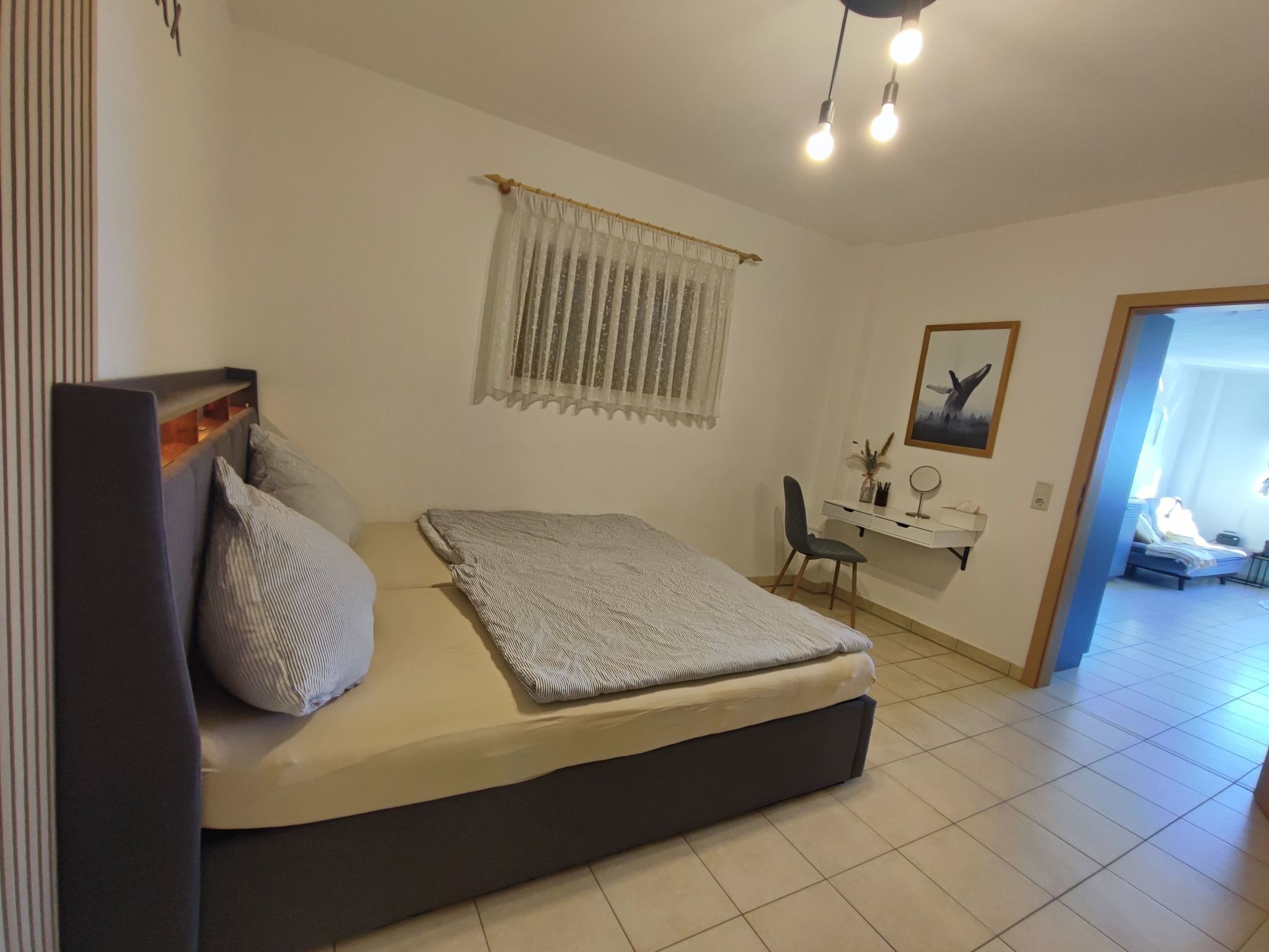 A bedroom with a bed, a desk, and a chair.