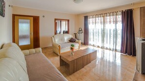 A living room with a sofa, a coffee table, a chair, a TV, and a window with curtains. - Apartment Renato by Interhome (Rovinj/Kanfanar)