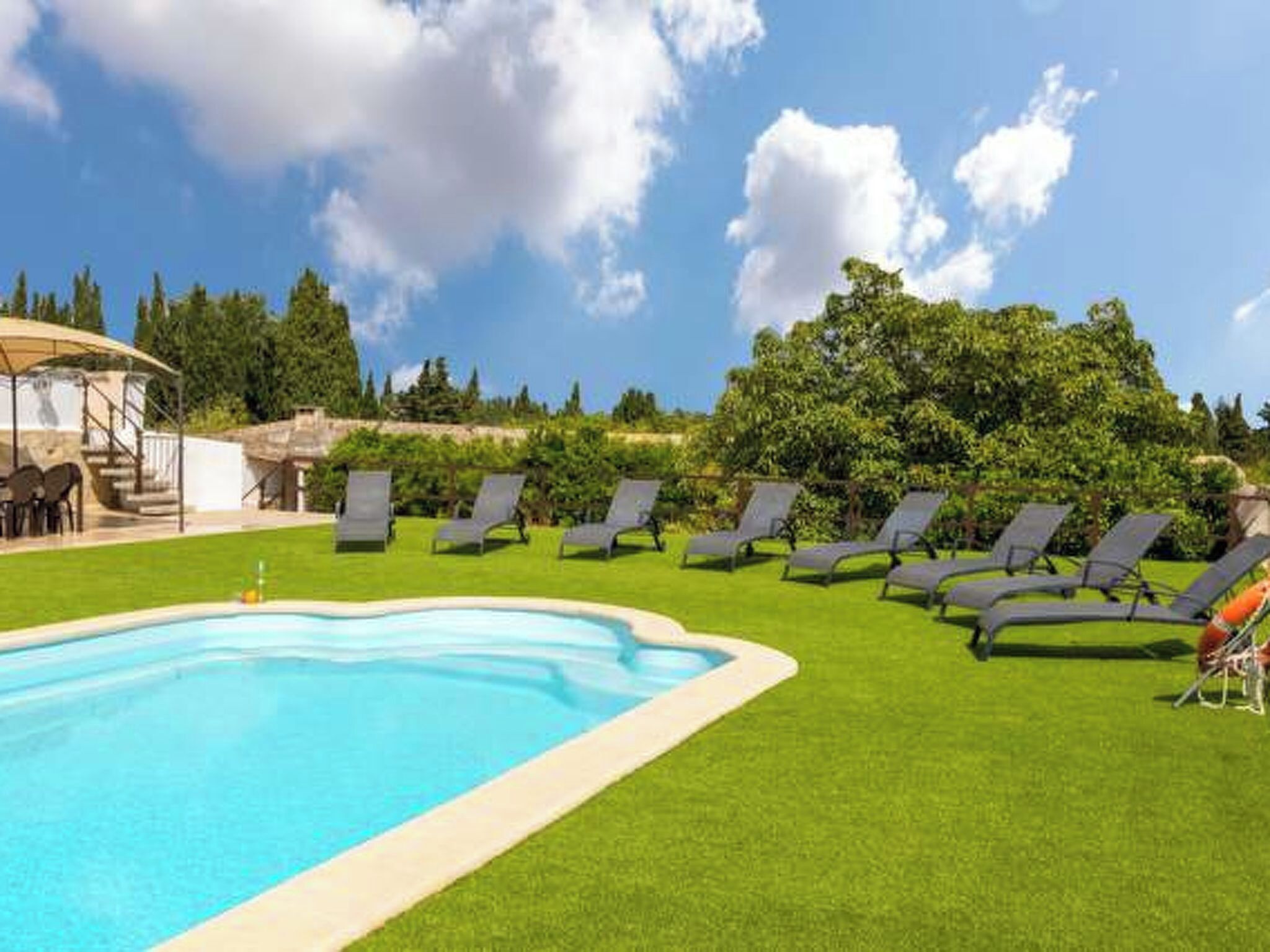 A swimming pool with lounge chairs and a covered seating area.
