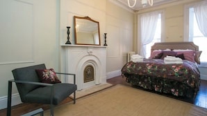 Un dormitorio con cama, sillón, chimenea y candelabro.