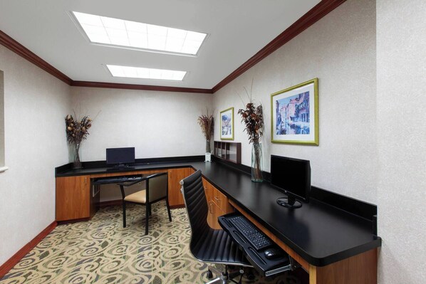 Zona de recepción con mostrador, dos sillones, una computadora y cuadros en la pared.