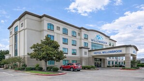 A multi-story hotel with a modern facade, large windows, and a prominent entrance with the hotel name. - Hotel Willowbrook (Houston)