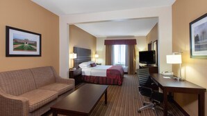 A hotel room with a bed, a desk, a chair, a sofa, and a television. - Hotel Willowbrook (Houston)