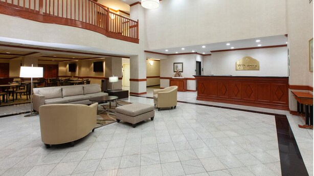 A spacious lobby with a high ceiling, a reception desk, and a seating area with sofas and a coffee table. - Hotel Willowbrook (Houston)