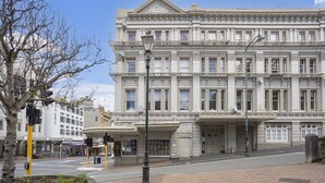 Um edifício histórico com fachada clássica, grandes janelas e entrada imponente.