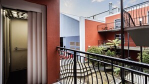 A balcony with a metal railing, a red building, and a blue building in the background. - Manor Place Stays Apartment one (Dunedin)
