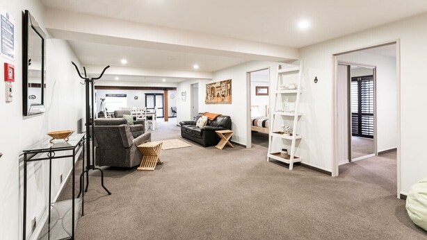 A spacious living area with a sofa, a coffee table, and a bookshelf. - Manor Place Stays Apartment one (Dunedin)