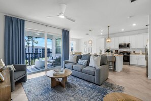 A modern living room with a grey sofa, a coffee table, and a view of a balcony.