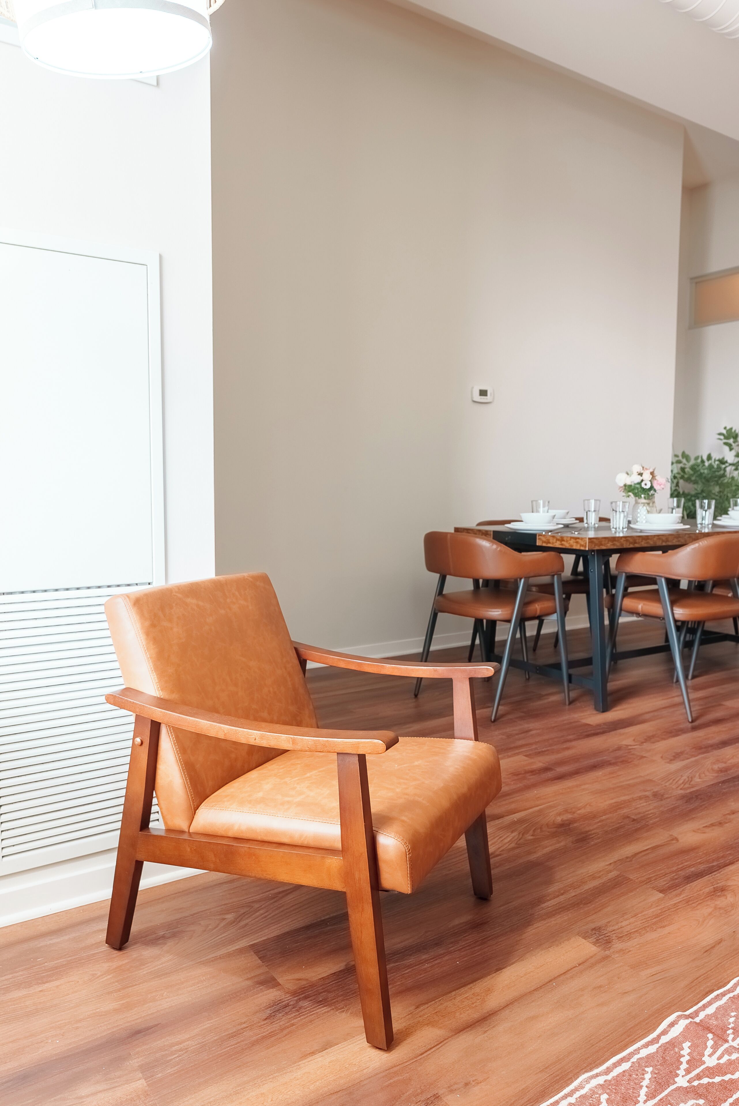 A dining area with a wooden table and chairs, a window with blinds, and a ceiling light fixture.