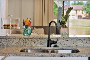 A kitchen with a granite countertop, stainless steel sink, and a black faucet. - Spacious 4-bedroom townhome in peaceful Davenport with AC 507 (Davenport)