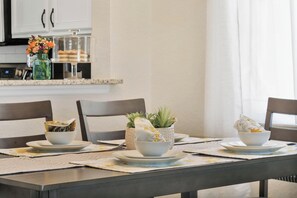 A dining table set with white bowls and plates, a vase with flowers, and a potted plant. - Spacious 4-bedroom townhome in peaceful Davenport with AC 507 (Davenport)