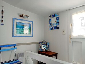 Ein Zimmer mit einem gerahmten Meeresbild, einer an der Wand befestigten abstrakten Kunst und einem Holztisch mit einer Uhr.
