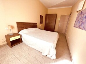 Une chambre à coucher comprenant un lit, une table de chevet, une armoire et un tableau accroché au mur.