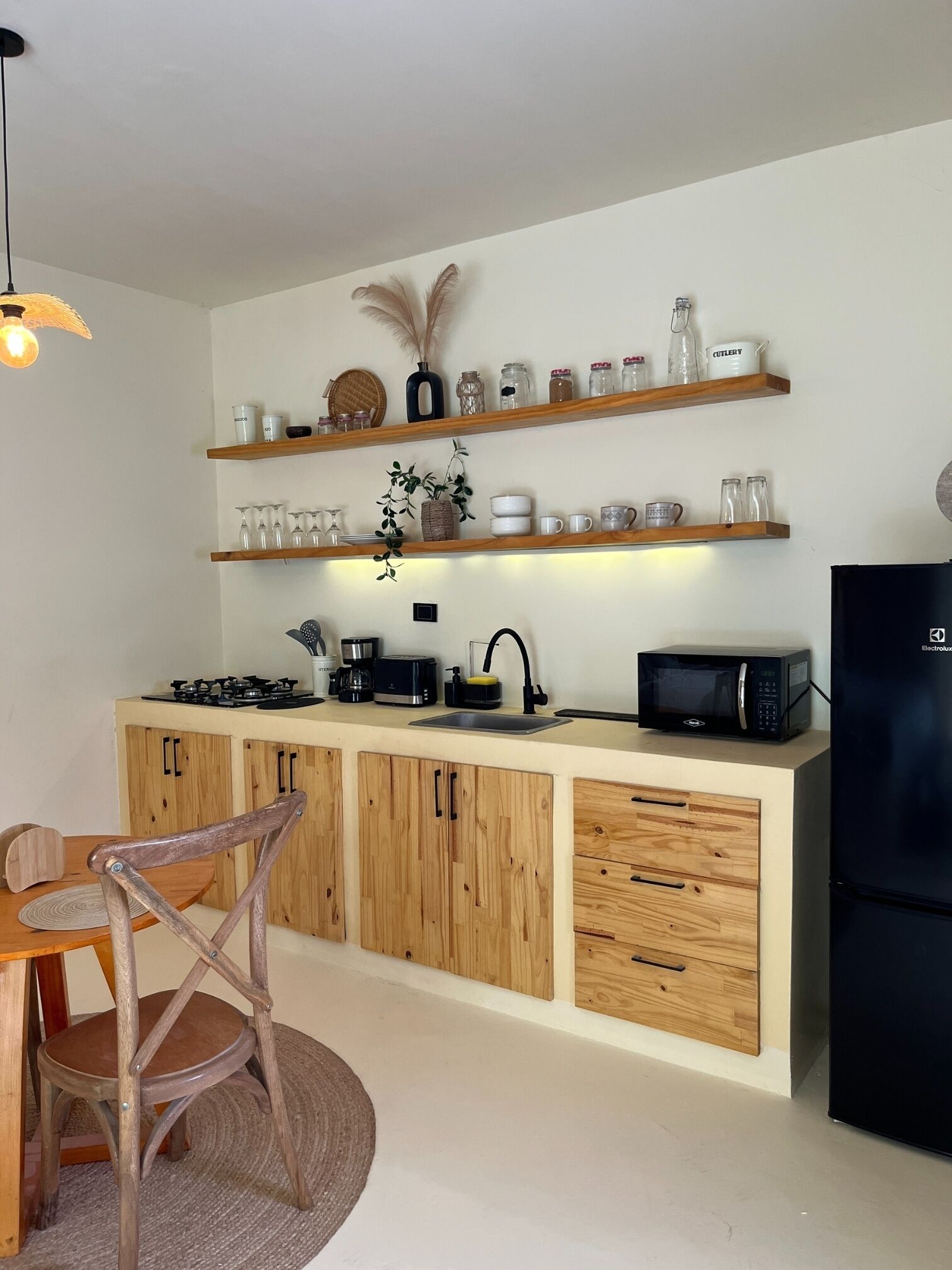 A modern kitchen with wooden cabinets, a built-in microwave, and a black refrigerator.
