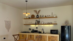 Une cuisine compacte avec des meubles en bois, une table à manger avec des chaises, un réfrigérateur noir et divers appareils de cuisine.