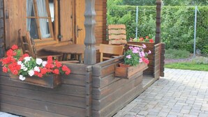 Una cabana de fusta amb un porxo, bancs de fusta i jardineres amb flors.