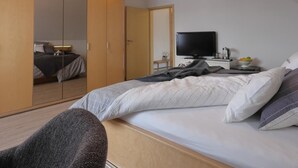 Habitació d'hotel moderna amb un llit gran, televisió, armari i zona de seients.