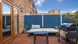 Una terraza de madera con una parrilla, un sofá y una mesa.