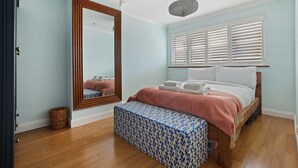 Un dormitorio con cama, banca, espejo y ventilador de techo.