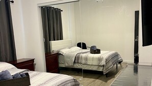 A hotel room with two beds, a large mirror, a wooden floor, and a TV. - Cozy 2-bedroom house in gorgeous Carson with AC for relaxing stays (Carson)
