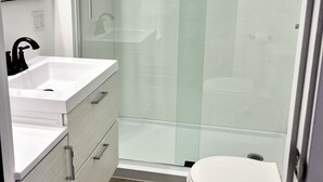 A modern bathroom with a glass shower enclosure, a white sink, and a toilet. - Cozy 2-bedroom house in gorgeous Carson with AC for relaxing stays (Carson)