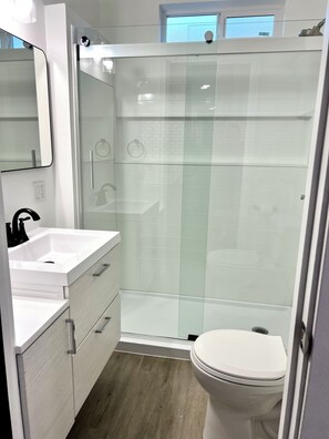 Une salle de bain moderne avec une douche à parois de verre, un lavabo blanc et des toilettes.